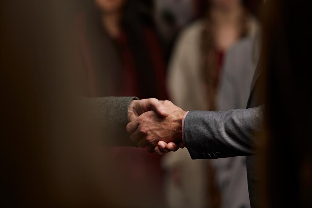 Close-up of 2 men making handshake in crowd